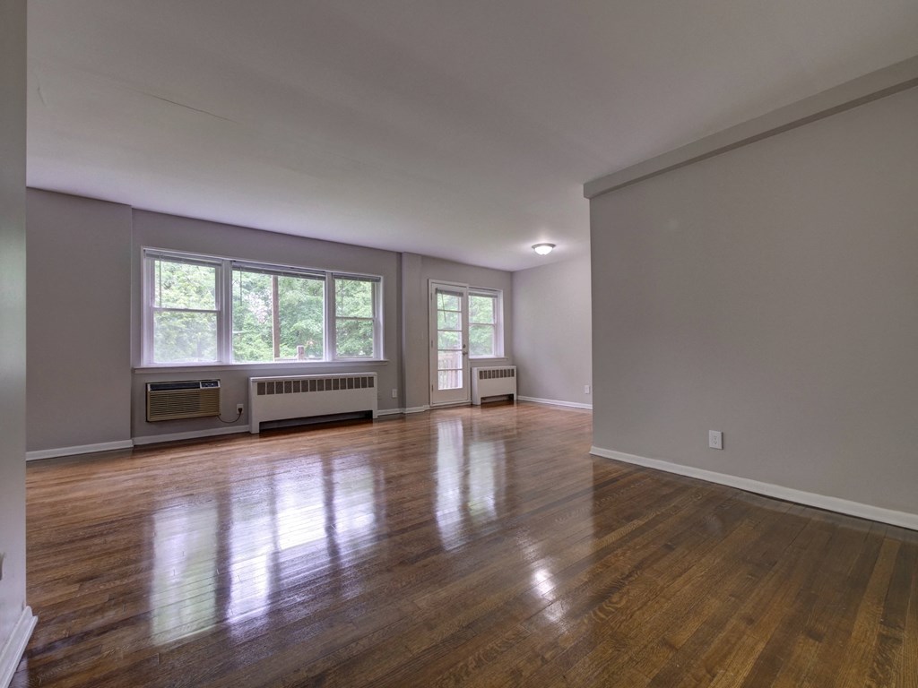 an empty living room with a hard wood floor and a window