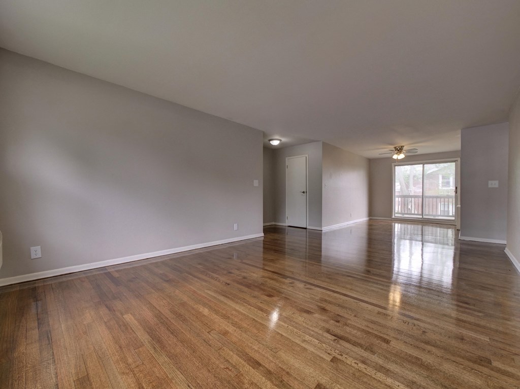 an empty living room with hardwood flooring and a window
