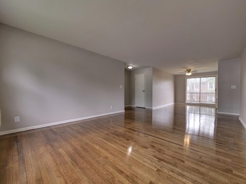 an empty living room with hardwood flooring and a window