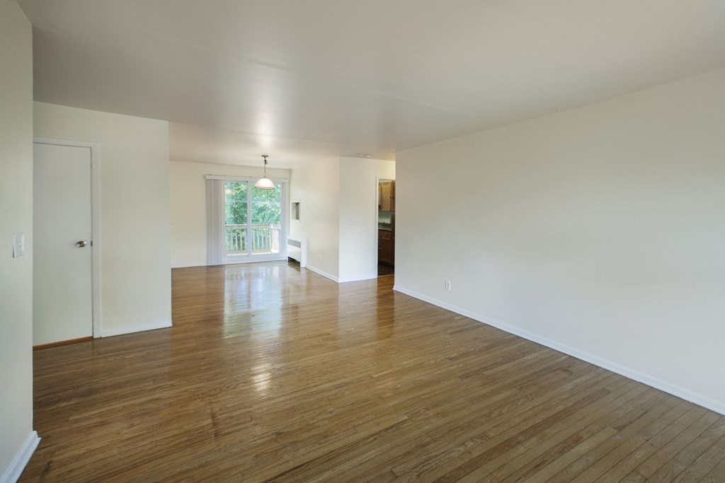 an empty living room with wood floors and white walls
