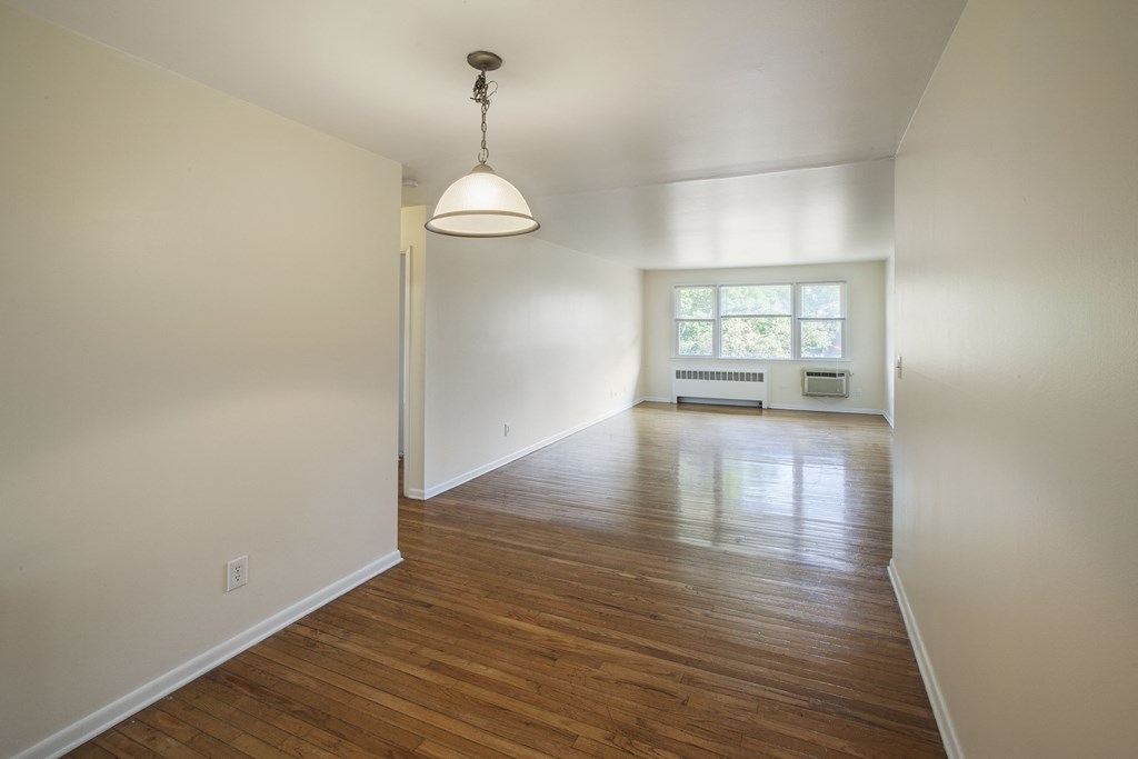 an empty living room with a hard wood floor and white walls