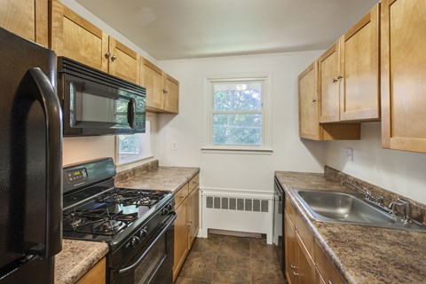a kitchen with wood cabinets and black appliances and granite counter tops