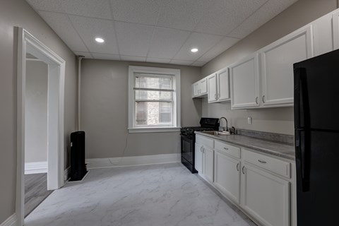 A kitchen with black appliances and white cabinets.