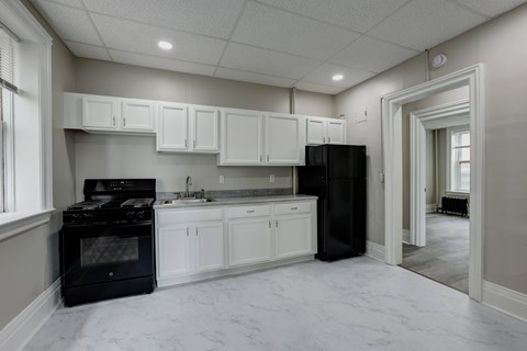 A kitchen with black appliances and white cabinets.