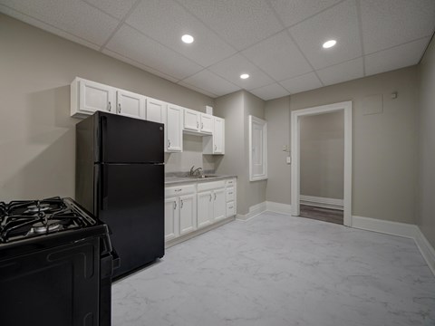 A kitchen with a black refrigerator and a black stove top.
