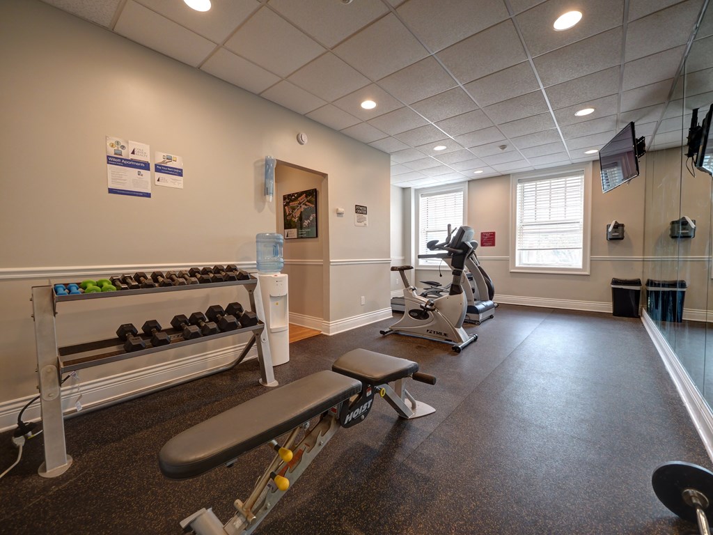 A gym with a bench, weights, and exercise equipment. at Willett Apartments, Albany, NY, 12210