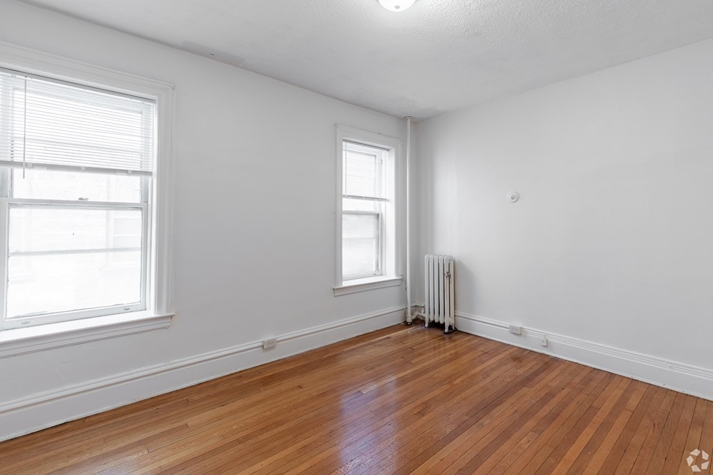 A room with wooden floors and two windows. at Willett Apartments, Albany, NY, 12210