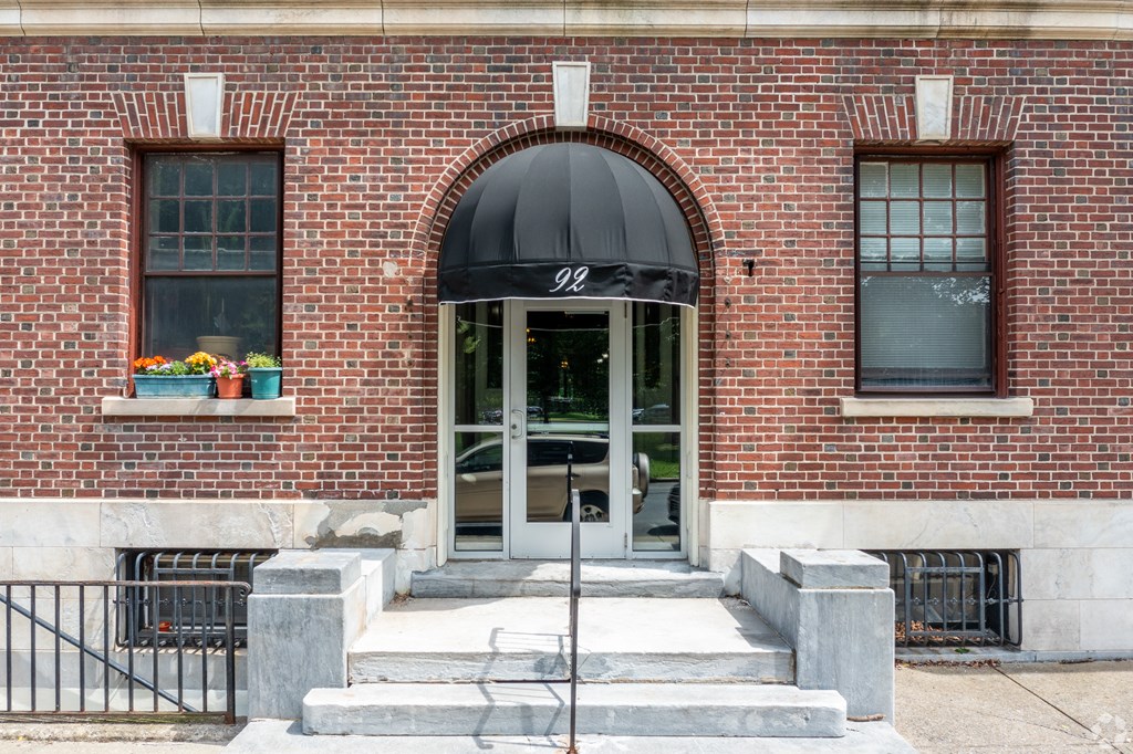 A brick building with a black awning and a glass door. at Willett Apartments, Albany, NY, 12210