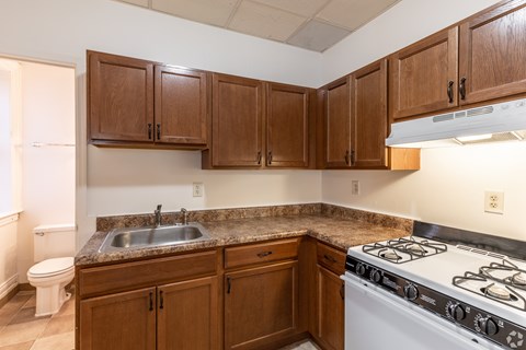 A kitchen with a white stove top oven and brown cabinets.