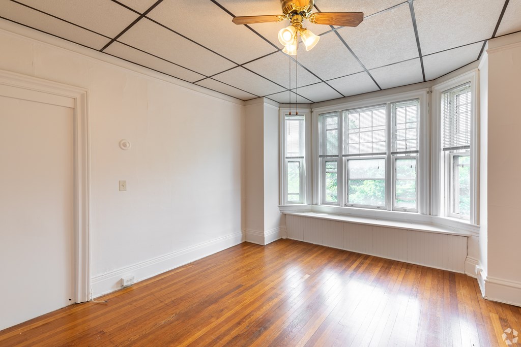 A room with a ceiling fan and a window with a view of trees. at Willett Apartments, Albany, NY, 12210