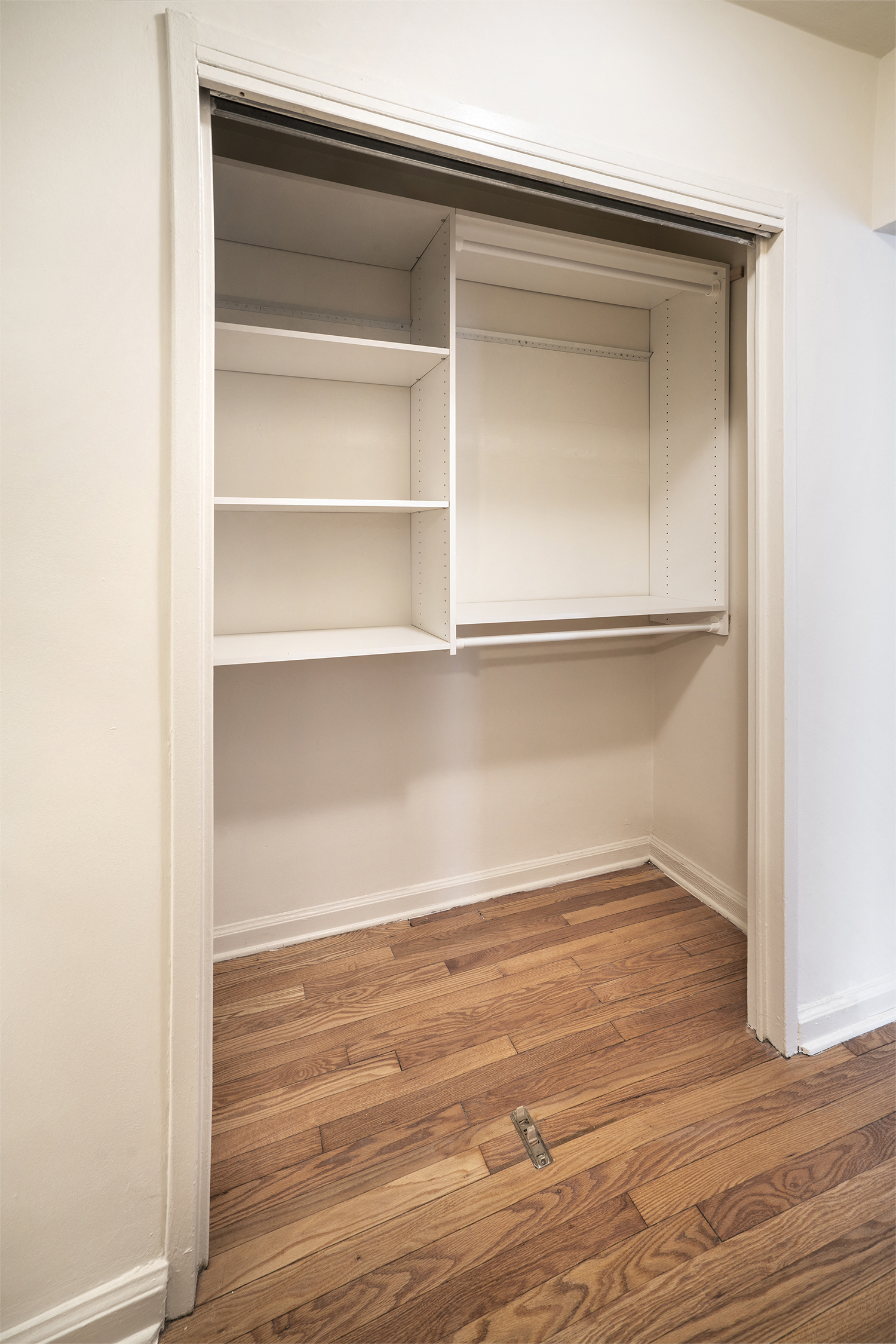 an empty closet with white shelves and a wood floor