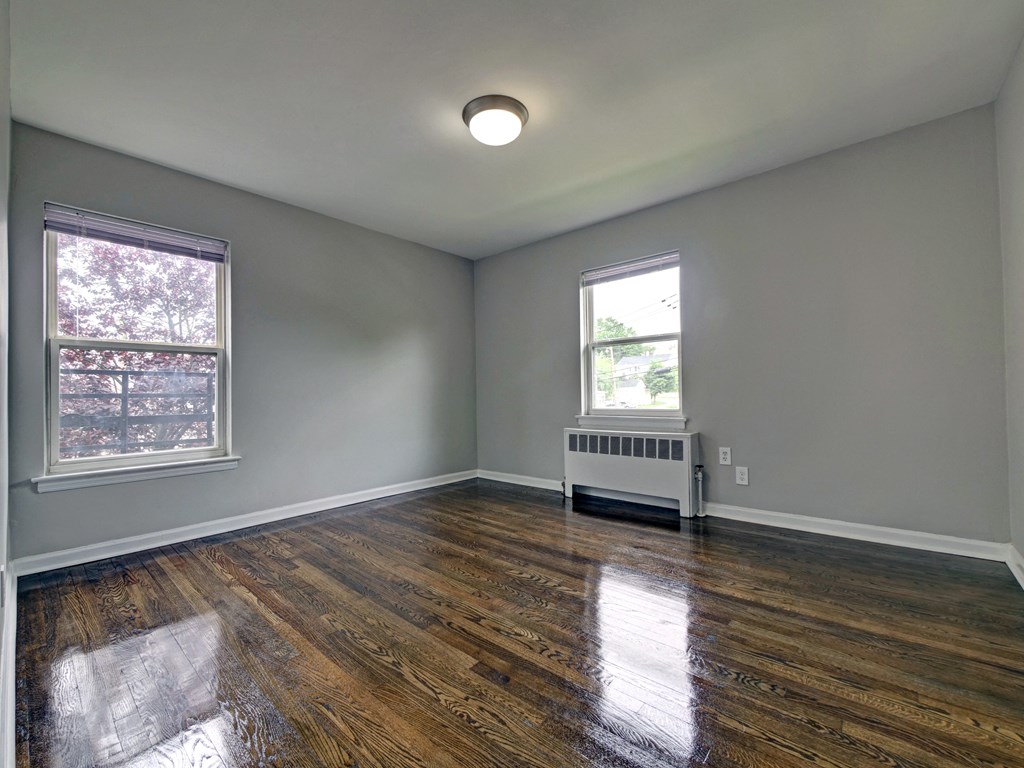 an empty room with a radiator and two windows