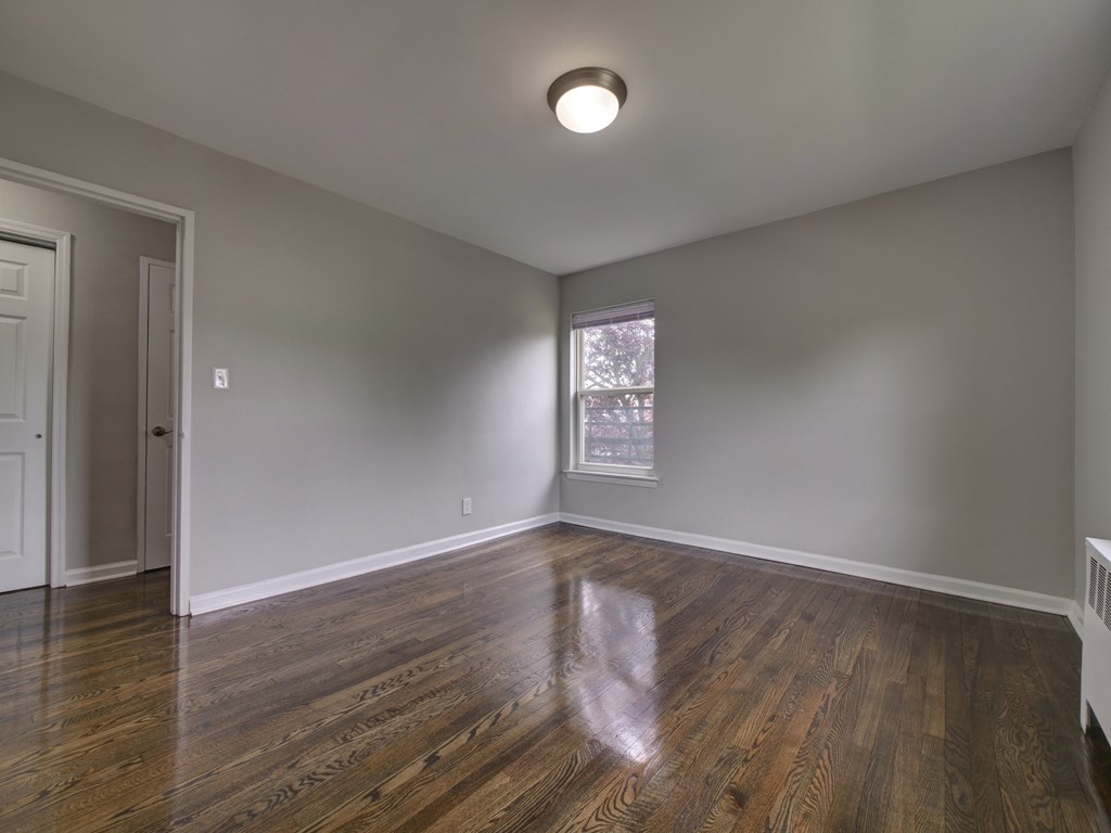 an empty living room with wood floors and a window
