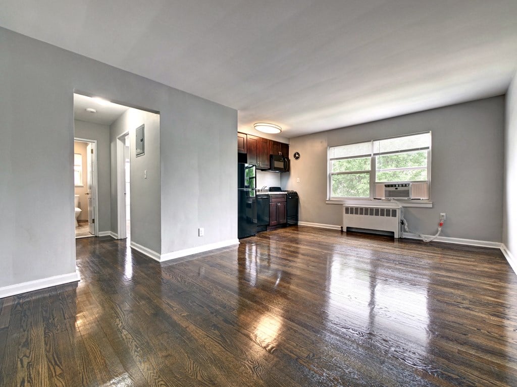 an empty living room with a large window and a kitchen