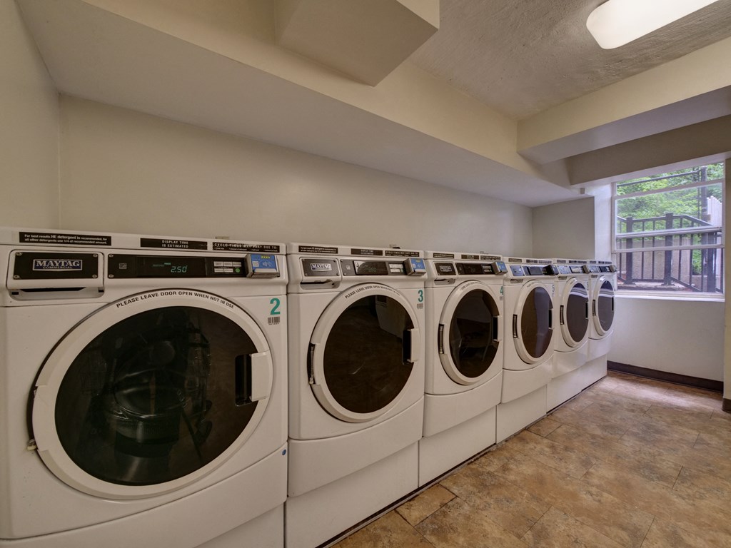 a washer and dryer in a laundry room with a row of washing machines