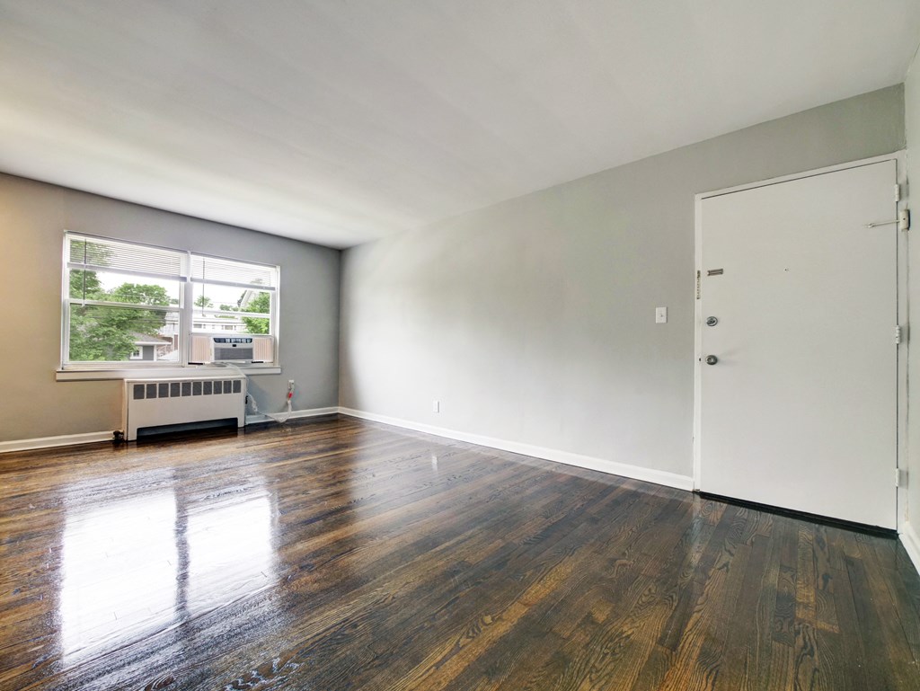 an empty living room with wood floors and a window