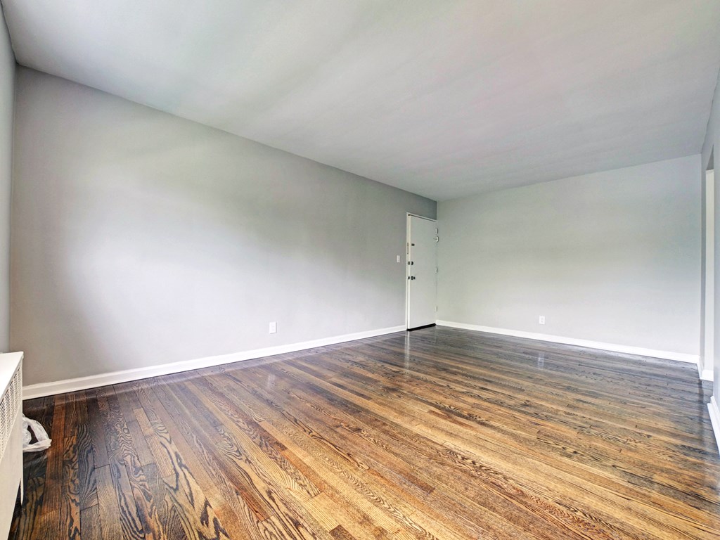 an empty living room with wood floors and white walls