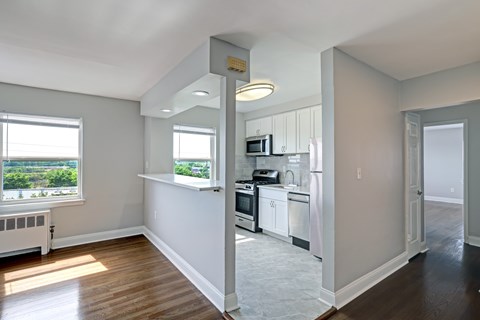 A kitchen with white cabinets and a window overlooking a green landscape.
