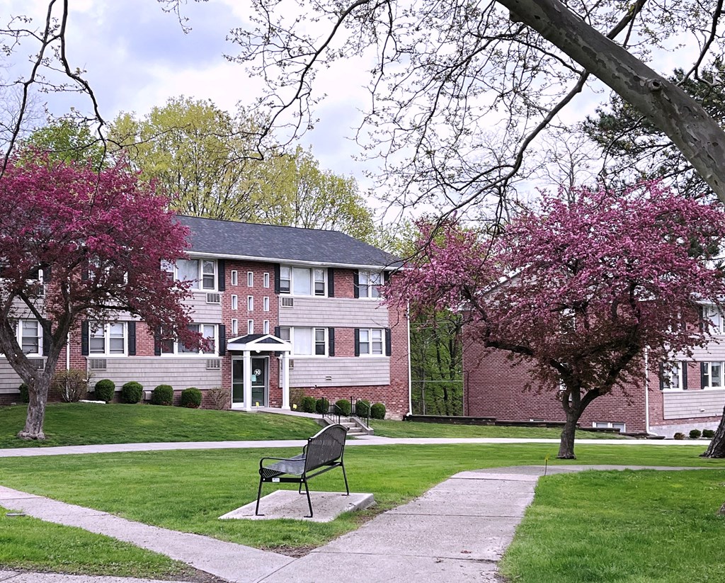 a bench sits in the middle of a grassy area in front of a brick building