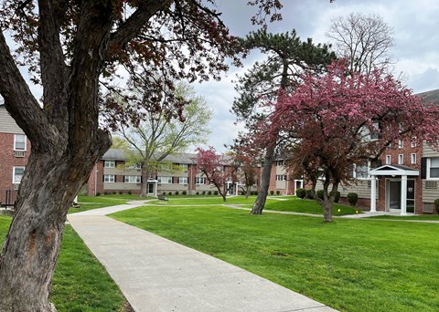 a sidewalk leads through a grassy area in front of a brick building