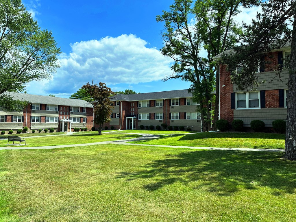 a grassy area with trees and buildings in the background