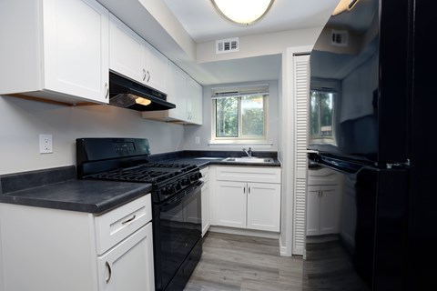 A kitchen with black appliances and white cabinets.