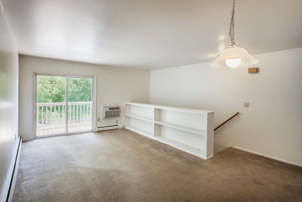 a bedroom with white walls and a sliding glass door leading to a balcony