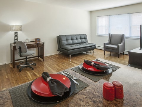 a living room with a leather couch and chairs and a table with a red chair