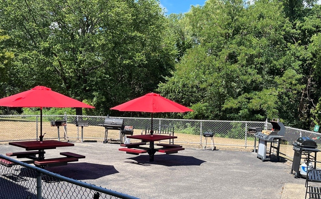 two picnic tables with red umbrellas in a park