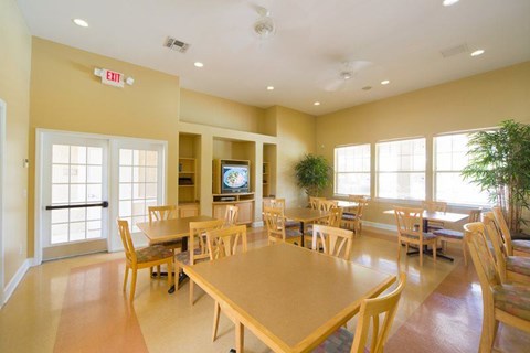 A room with tables and chairs and a TV on the wall.