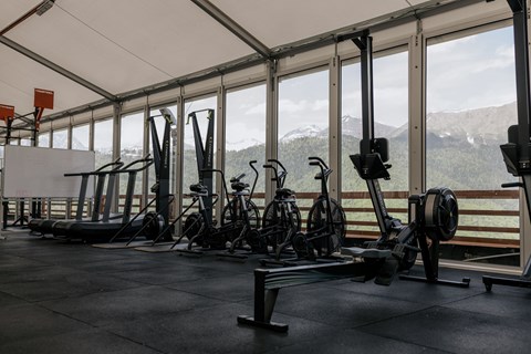 A gym with exercise equipment and a view of the mountains outside the windows.