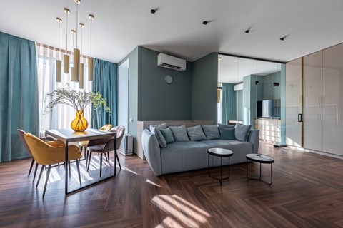 A modern living room with a dining table and a grey couch.