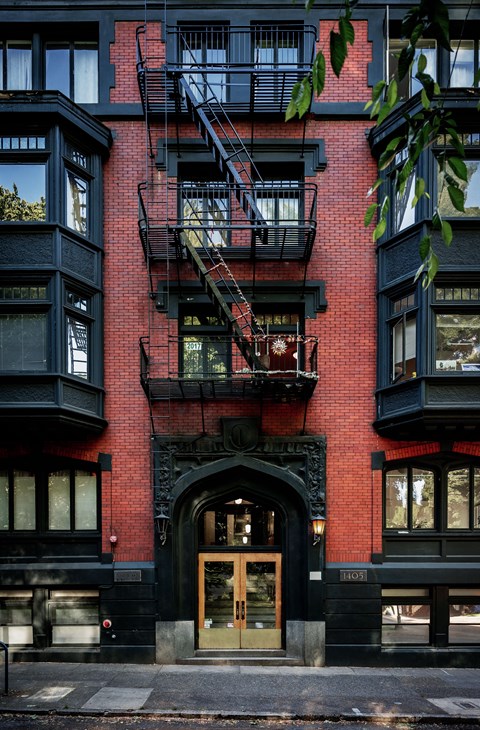A red brick building with a black door and a fire escape.