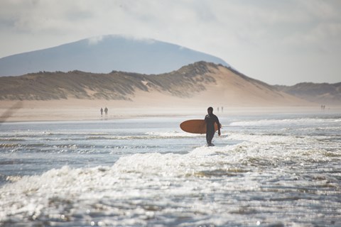 A person with a surfboard is walking into the ocean.
