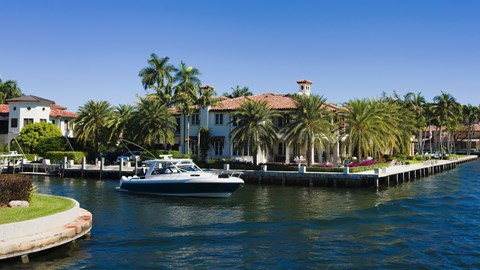 A boat is docked in front of a house with a dock.