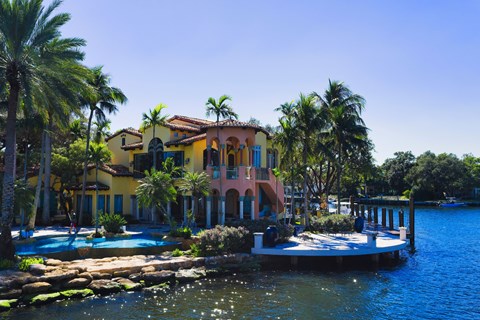 A yellow house with a pool in front of it.