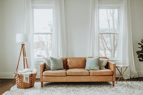 A living room with a tan couch, a white rug, and a white floor lamp.