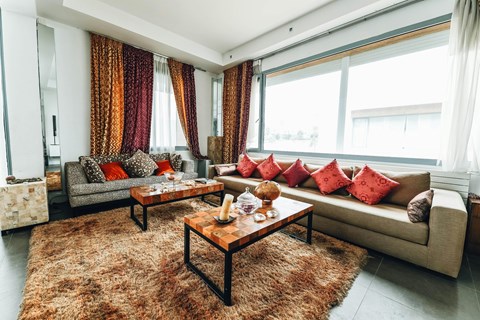 A living room with a couch, coffee table, and curtains.