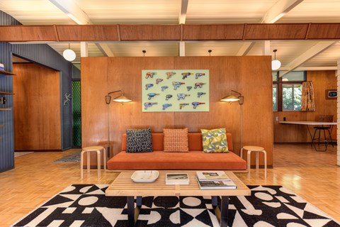 A living room with a sofa, a coffee table, and a large painting on the wall.