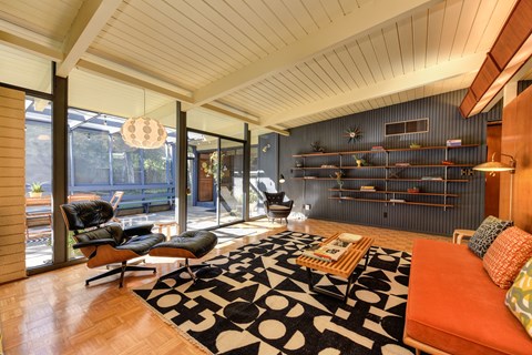 A living room with a black and white rug and a red couch.