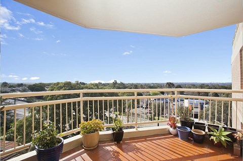 A balcony with potted plants and a view of the street below.