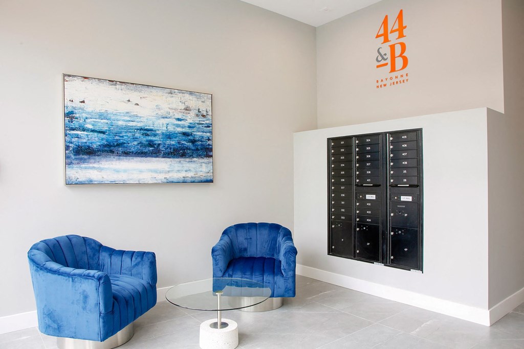 a room with two blue chairs and a glass table with a painting on the wall