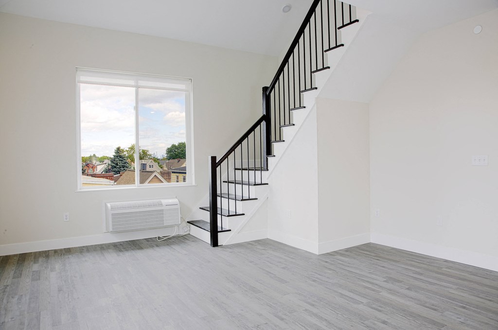 an empty room with a staircase and a large window