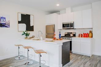 a kitchen with white cabinets and a large white island with two stools