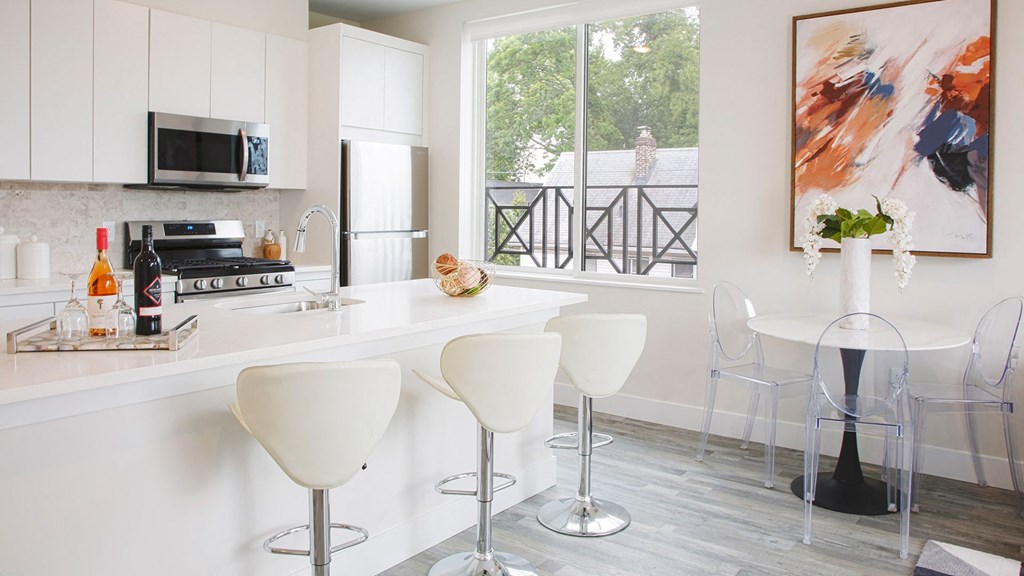 a kitchen with white cabinets and a large window