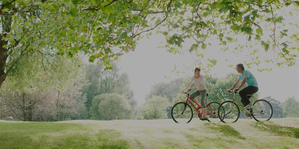a man and a woman riding bikes in a park