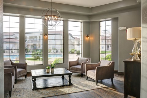 A living room with a large window and a view of a pool and houses.