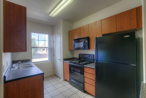 A kitchen with black appliances and wooden cabinets.