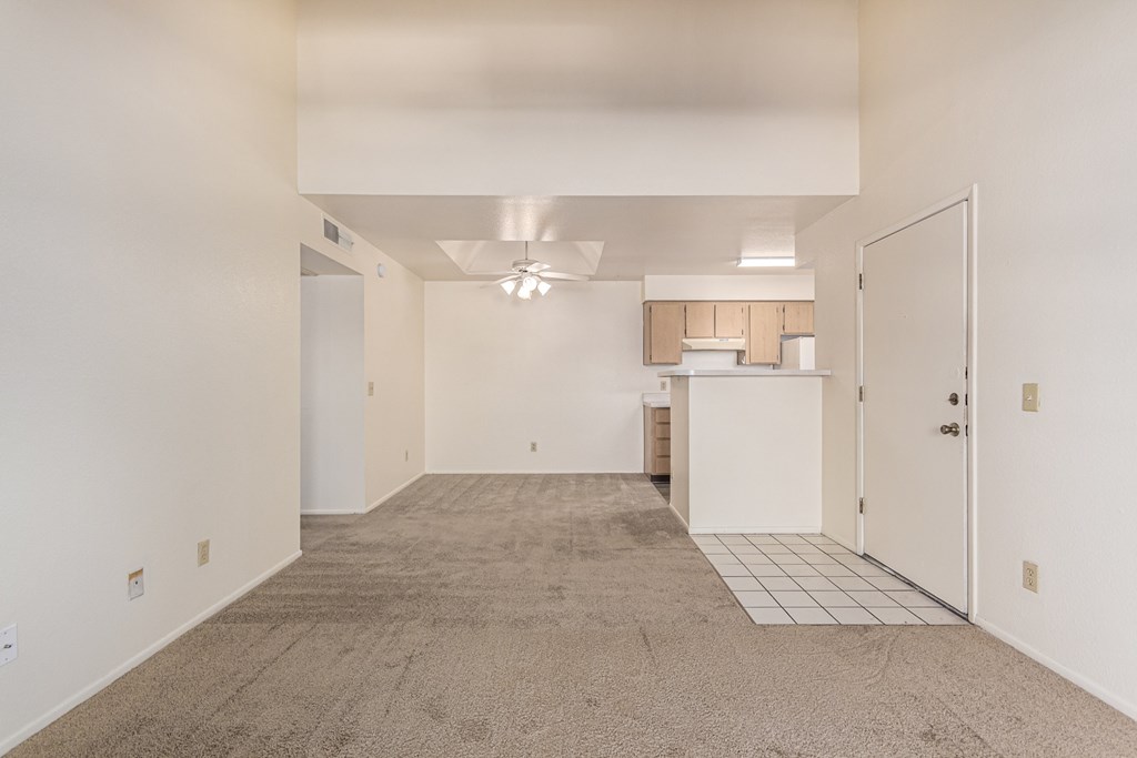 A spacious room with a carpeted floor and a ceiling fan.