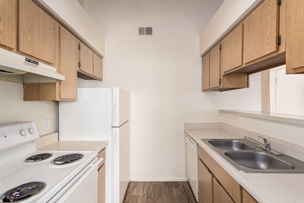 A kitchen with white appliances and wooden cabinets.